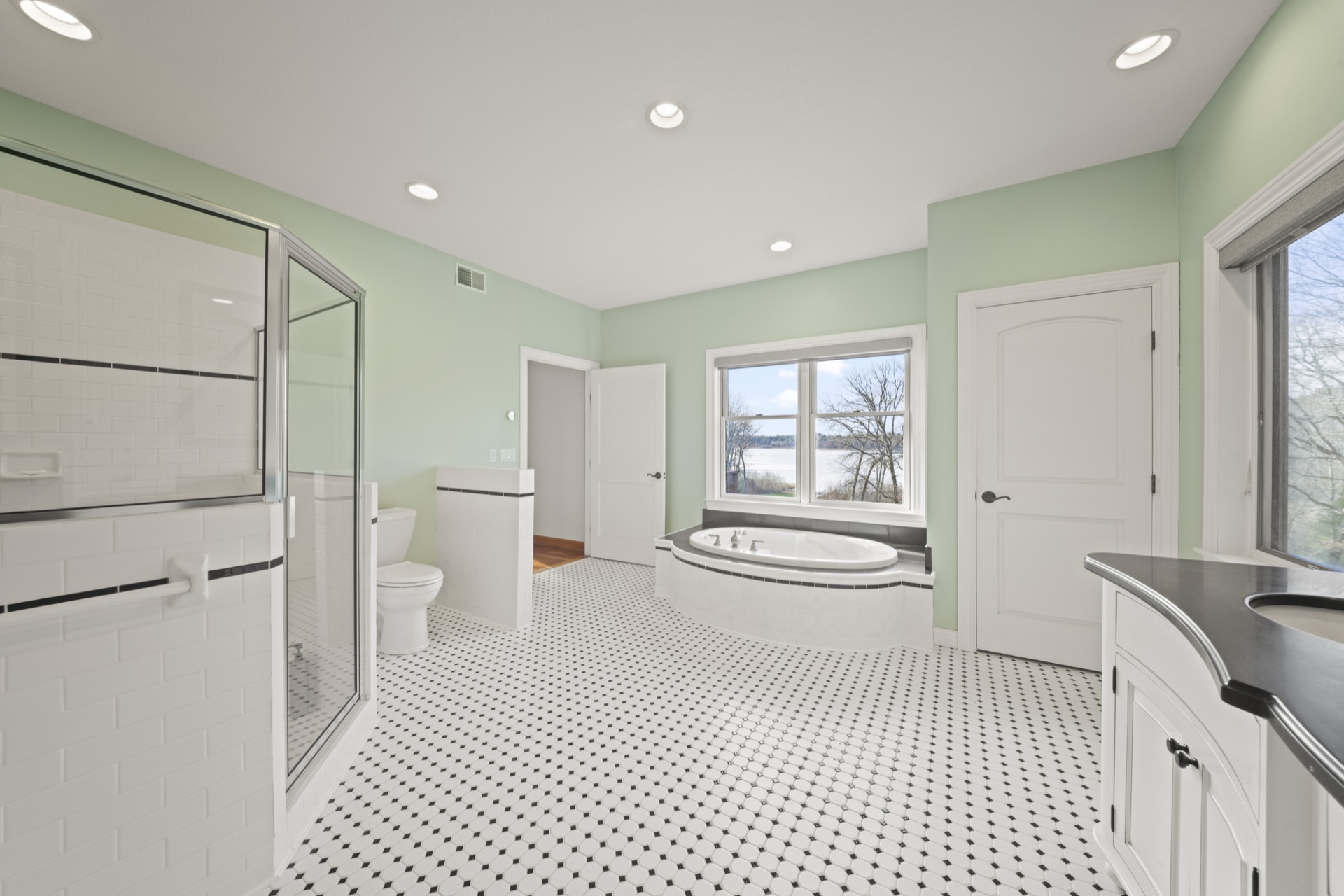Primary bathroom with soaking tub and panoramic Long Lake views