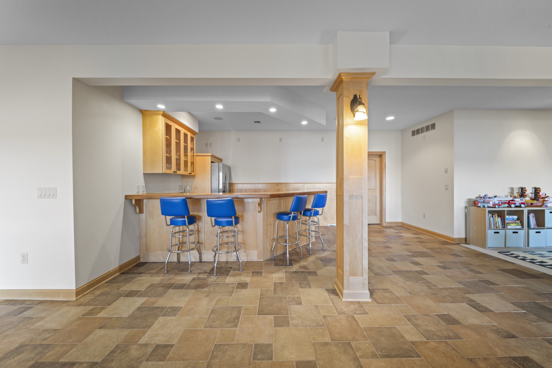 Wet bar kitchenette with seating and refrigerator in recreation room